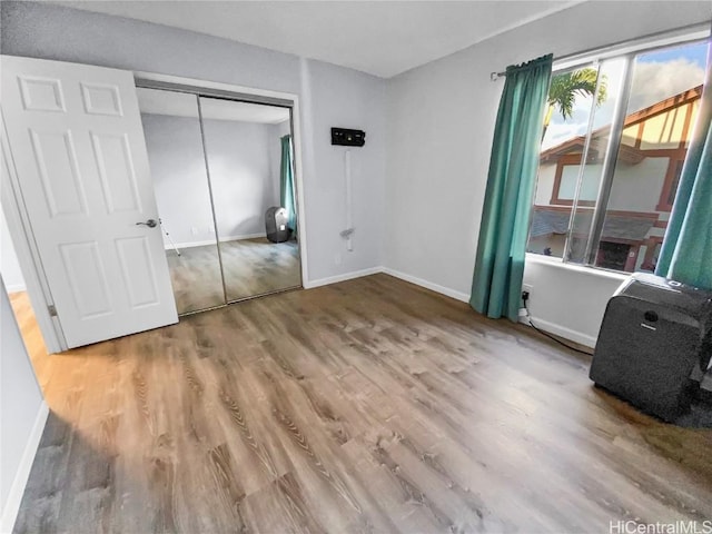 unfurnished bedroom featuring a closet, wood finished floors, and baseboards