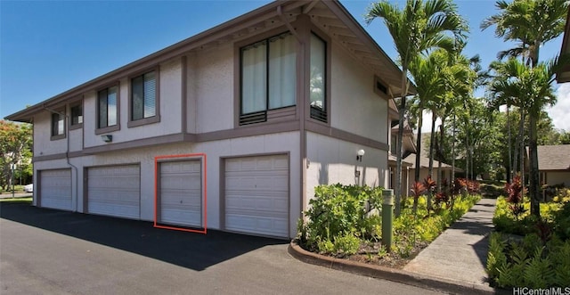 view of side of home featuring a garage and stucco siding