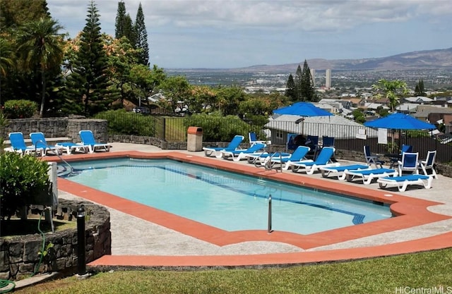 community pool with a patio area, fence, and a mountain view