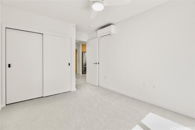 unfurnished bedroom featuring a ceiling fan, an AC wall unit, a closet, freestanding refrigerator, and carpet