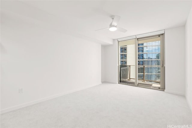 empty room with a ceiling fan, carpet, expansive windows, and baseboards