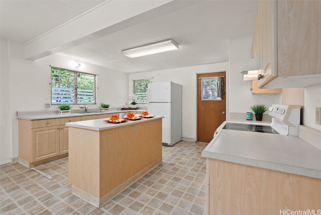 kitchen featuring range with electric cooktop, a kitchen island, freestanding refrigerator, light countertops, and light brown cabinetry