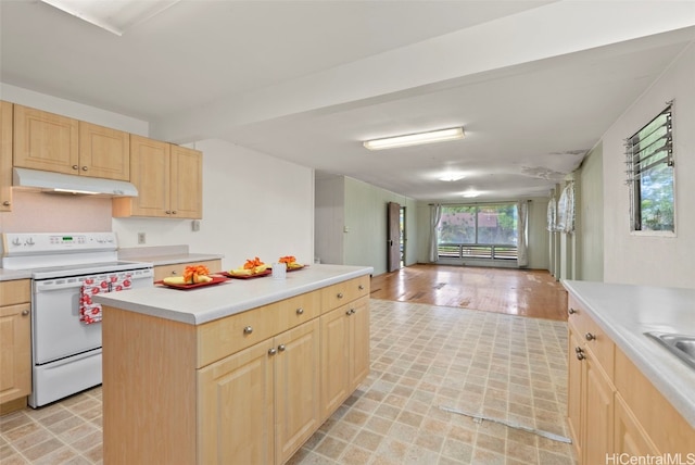 kitchen with electric stove, light brown cabinetry, light countertops, and under cabinet range hood