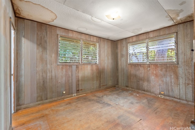 spare room featuring wooden walls, a textured ceiling, and wood finished floors