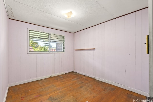 empty room featuring a textured ceiling, baseboards, and hardwood / wood-style flooring