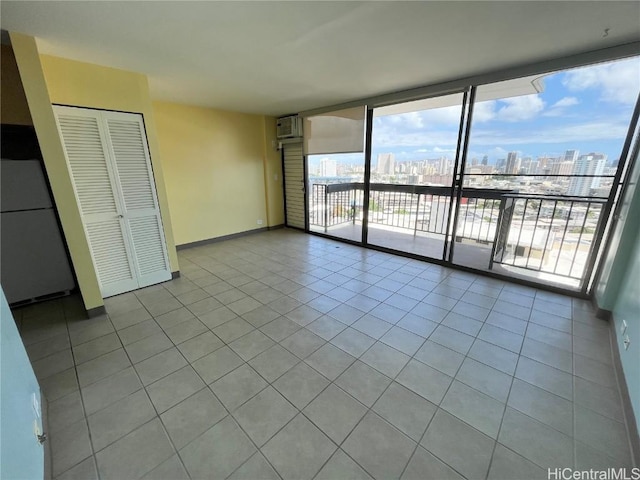 unfurnished room with expansive windows, light tile patterned floors, a view of city, and baseboards