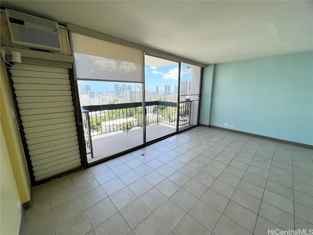 spare room featuring a city view, a wall unit AC, light tile patterned floors, a wall of windows, and baseboards