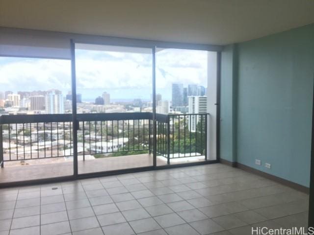 unfurnished room with a view of city, expansive windows, tile patterned flooring, and baseboards