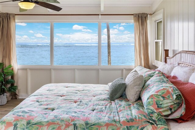 bedroom featuring wood finished floors, a ceiling fan, a decorative wall, and a water view