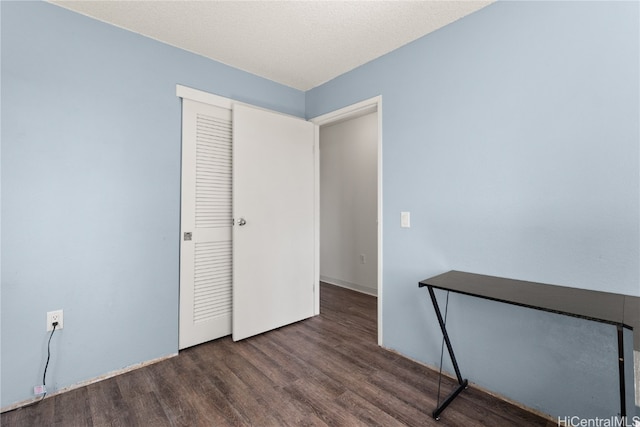 unfurnished bedroom featuring a closet, a textured ceiling, and wood finished floors