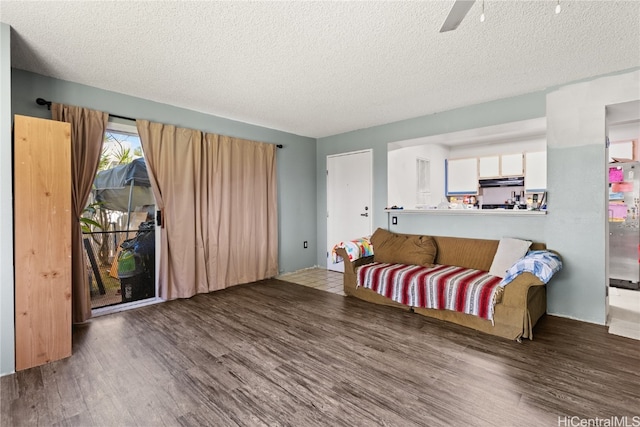 living area with a ceiling fan, a textured ceiling, and wood finished floors