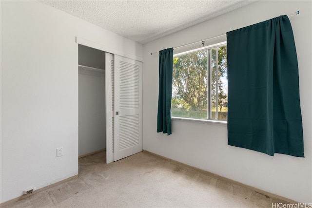 unfurnished bedroom featuring carpet floors, a closet, multiple windows, and a textured ceiling