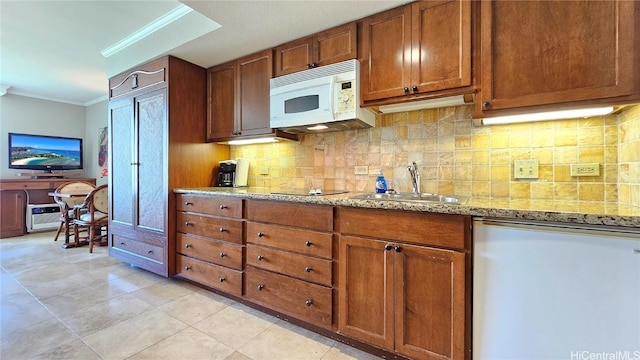 kitchen featuring white appliances, light stone counters, ornamental molding, brown cabinets, and a sink