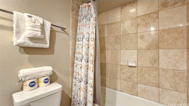 bathroom with a textured wall, toilet, and shower / bathtub combination with curtain