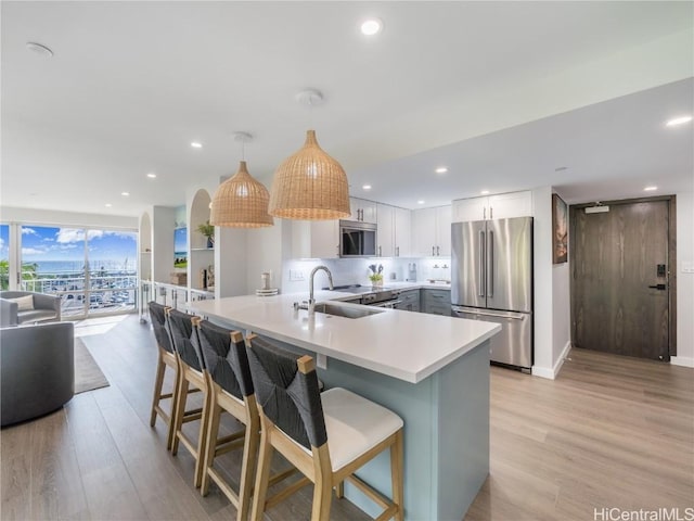 kitchen with appliances with stainless steel finishes, a sink, a peninsula, and light wood finished floors