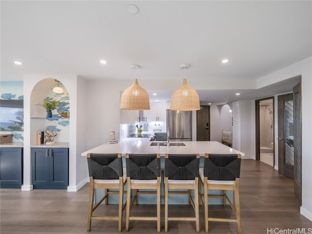 kitchen featuring dark wood-style floors, a kitchen breakfast bar, high end fridge, light countertops, and a sink