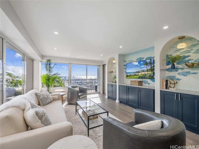 living area featuring recessed lighting, arched walkways, and light wood finished floors