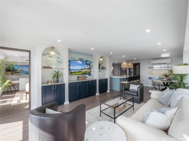 living area featuring recessed lighting, light wood-style flooring, and a wall mounted AC