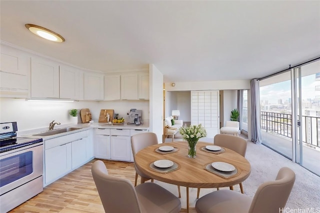 kitchen with stainless steel electric range oven, a sink, light countertops, white cabinets, and floor to ceiling windows