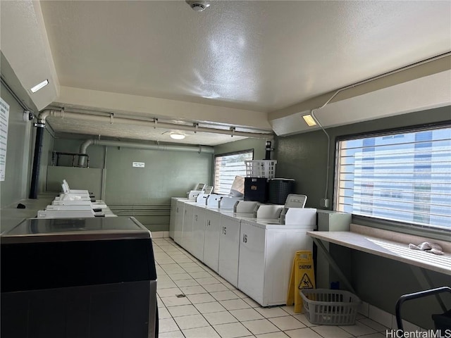 common laundry area featuring light tile patterned floors, a textured ceiling, and separate washer and dryer