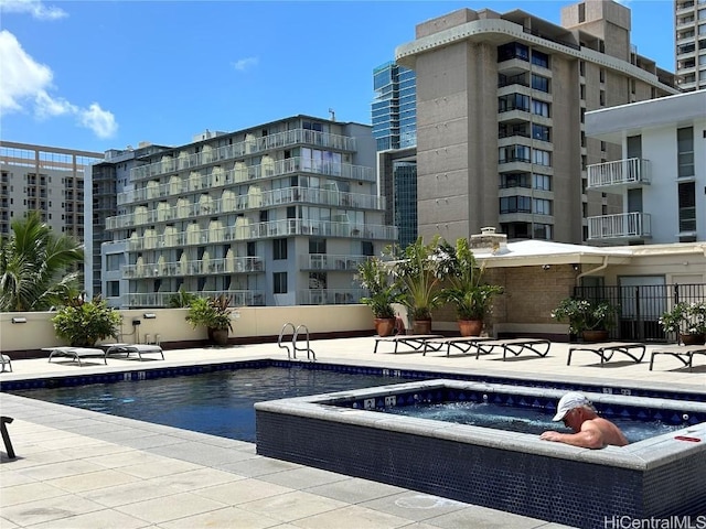 view of swimming pool with a patio, fence, and a hot tub