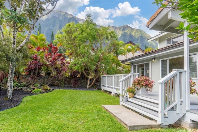 view of yard featuring a deck with mountain view and fence