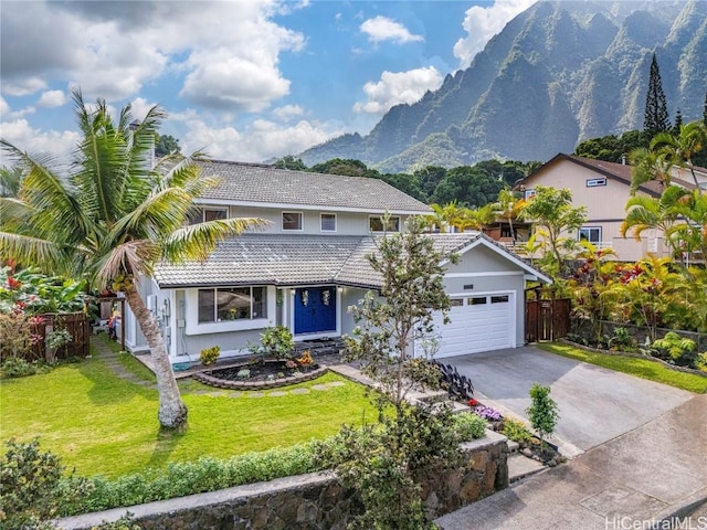 traditional home with driveway, a garage, fence, a mountain view, and a front lawn