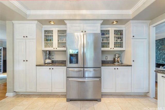 kitchen featuring dark stone counters, stainless steel refrigerator with ice dispenser, and white cabinetry