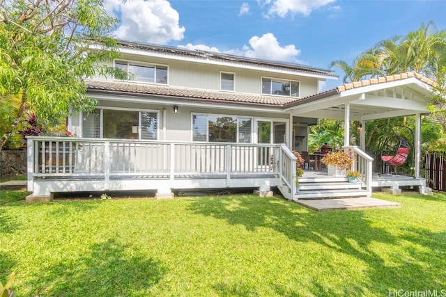 rear view of house with a tiled roof, a lawn, and a wooden deck