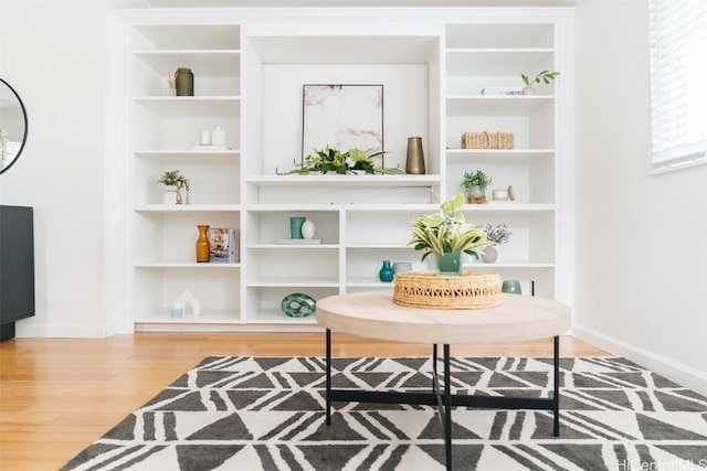 sitting room with built in shelves, baseboards, and wood finished floors