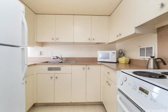 kitchen with white appliances, visible vents, cream cabinets, light countertops, and a sink