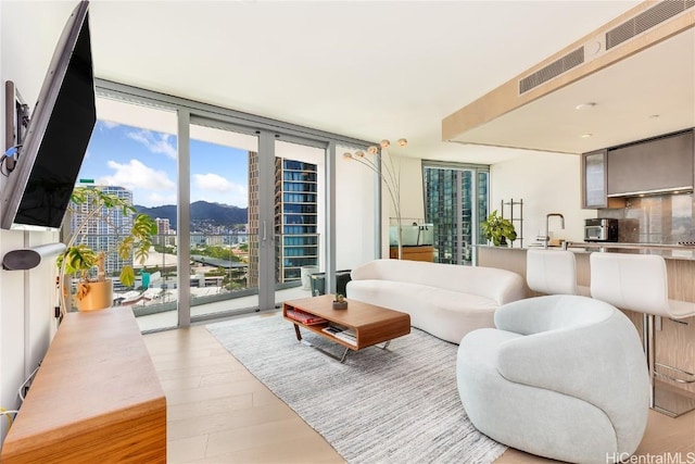 living room with visible vents, wood finished floors, and expansive windows