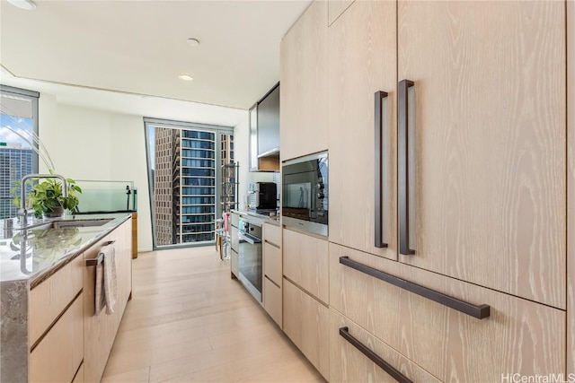 kitchen with light stone counters, light brown cabinets, oven, floor to ceiling windows, and black microwave