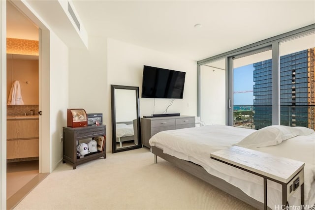 bedroom featuring a sink, visible vents, light carpet, and ensuite bath