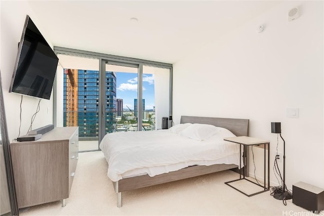 bedroom with a wall of windows, a view of city, access to outside, and light carpet