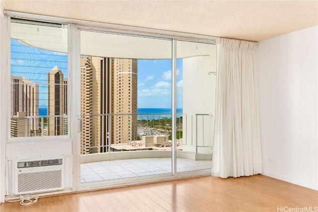 doorway featuring a textured ceiling, a water view, wood finished floors, a wall of windows, and a wall mounted air conditioner