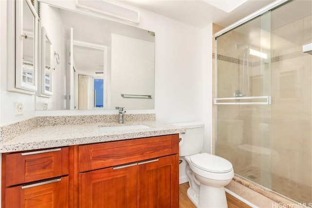 bathroom with a stall shower, vanity, and toilet