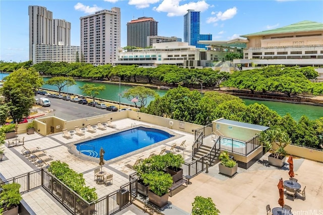 pool with a water view, a view of city, fence, and a patio