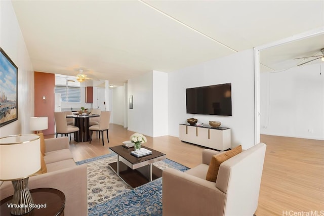 living area with light wood-style floors and a ceiling fan