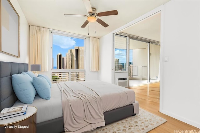 bedroom with a city view, wood finished floors, a ceiling fan, baseboards, and access to outside