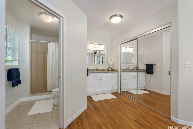 full bath featuring a sink, wood finished floors, a stall shower, and double vanity