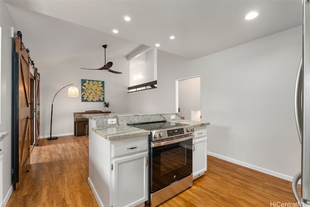 kitchen featuring lofted ceiling, light wood-style flooring, stainless steel appliances, white cabinets, and a barn door