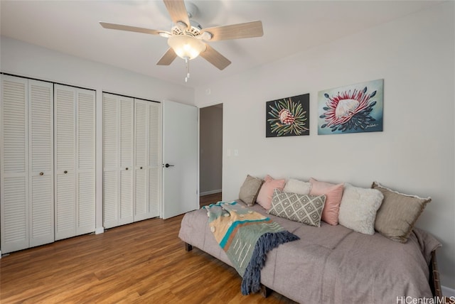 bedroom with two closets, a ceiling fan, and wood finished floors