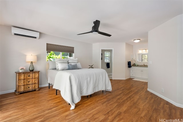 bedroom featuring light wood finished floors, a wall mounted AC, baseboards, and a sink