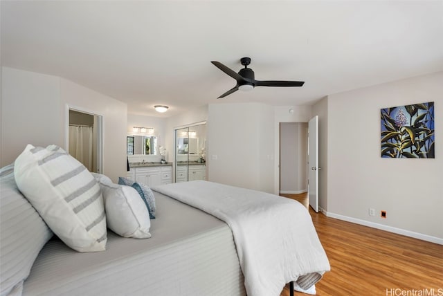 bedroom featuring ceiling fan, light wood-type flooring, baseboards, and ensuite bath