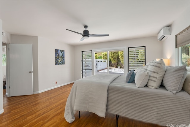 bedroom with multiple windows, access to outside, wood finished floors, and a wall mounted AC