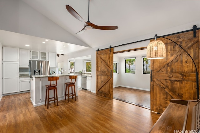 kitchen with a breakfast bar, a barn door, light countertops, and appliances with stainless steel finishes