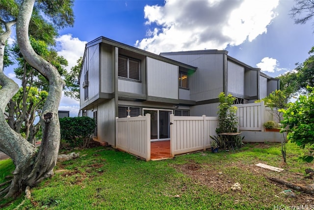 back of property with fence and a lawn