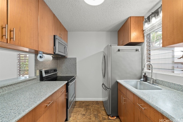 kitchen with brown cabinetry, stainless steel appliances, and a sink