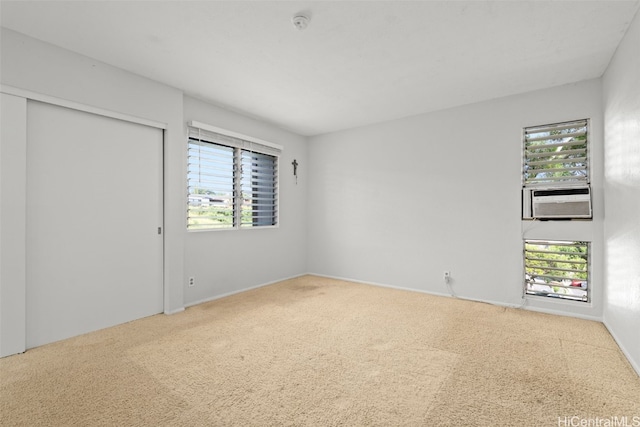 unfurnished bedroom with carpet floors, a closet, multiple windows, and cooling unit